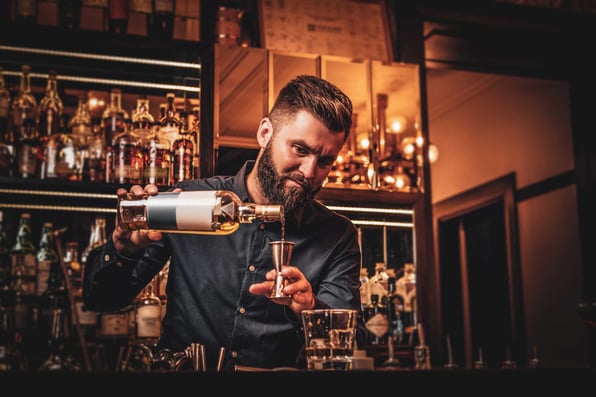 Bar manager is making drinks at the bar. This picture is in the Game-Changing Bar Marketing Ideas blog post.