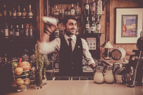 Man in black suit jacket holding clear glass bottle