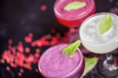 Clear drinking glass with pink liquid and green leaf